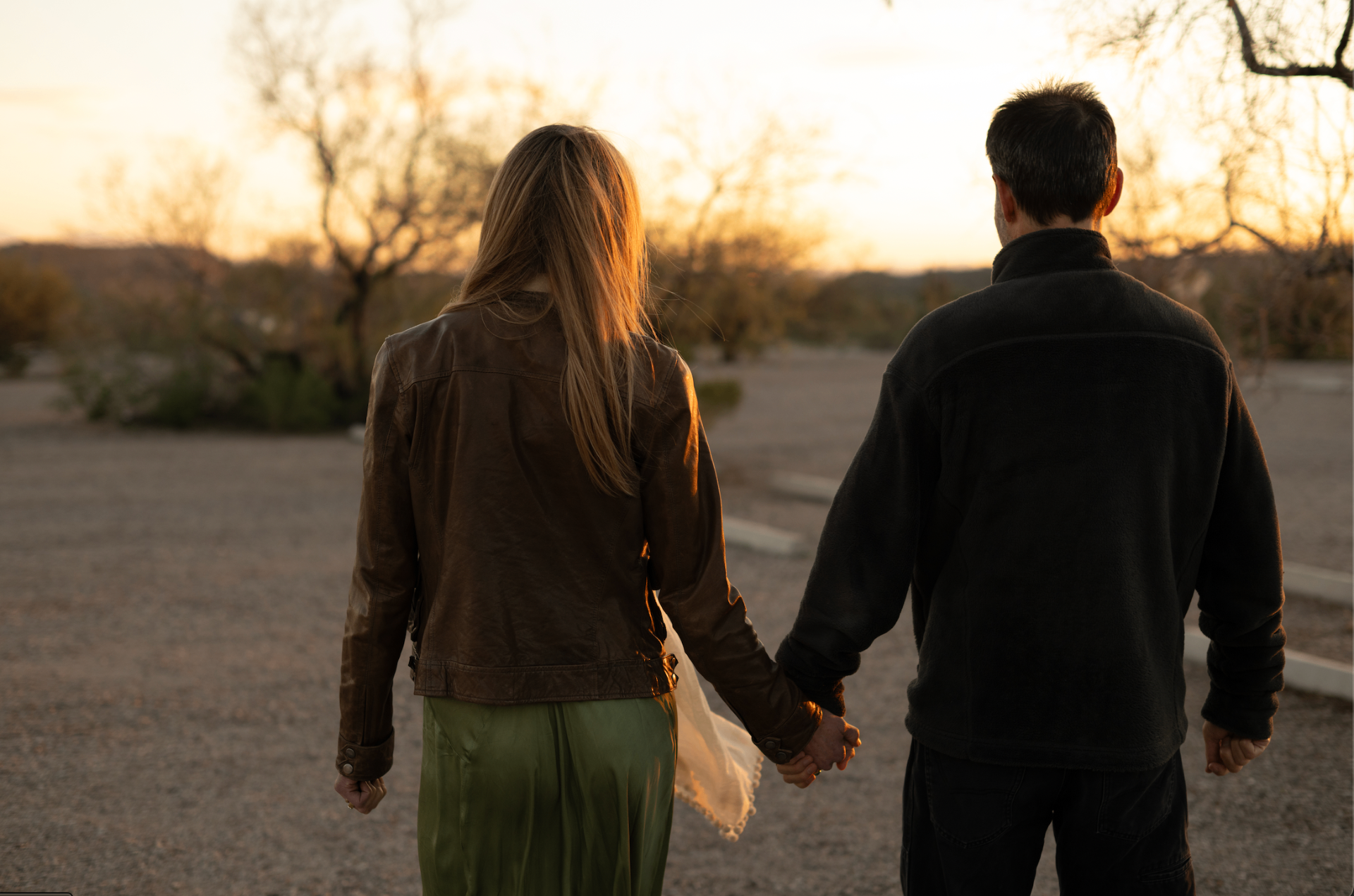 Kristy and Jason holding hands in the desert at sunset